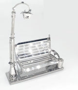 Het Parkbankje met Lantaarn Metalen Bouwpakket van SlimSpul nederland b.v. is een miniatuur stadsgezicht met een glanzend zilveren bankje, straatlantaarn en afvalbak op een gestructureerde voet, perfect voor verzamelaars en modelbouwliefhebbers.