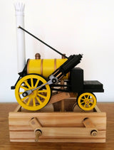 De Stephenson's Rocket Stoomlocomotief Houtconstructie - Historisch Treinmodel (Timberkits Expert) van SlimSpul nederland b.v. heeft grote gele wielen en een zwarte schoorsteen, perfect voor treinliefhebbers.