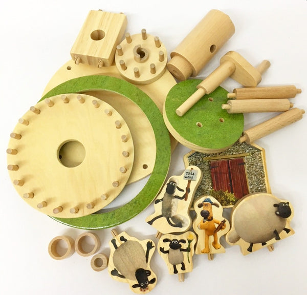 De Aardman Flock Roundabout Houtconstructie - Draaimolen Model (Timberkits Beginner) van SlimSpul nederland b.v. bevat houten onderdelen, groene planken, haringen en schapen- en hondenfiguren bij een rode schuurdeur.