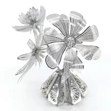 Het Vaasje met Bloemen Metalen Bouwpakket van SlimSpul nederland b.v. is een sierlijke decoratie met fijne, kanten bloemdetails en een gedetailleerde basis - een schitterend metalen modelbouwstuk tegen een witte achtergrond.