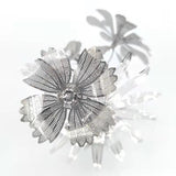 Close-up van het Vaasje met Bloemen Metalen Bouwpakket van SlimSpul nederland b.v.; metallic zilveren bloemen met geperforeerde bloemblaadjes creëren een moderne, artistieke look tegen een witte achtergrond.