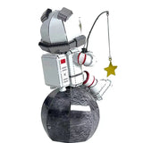The Astronaut Vissend naar Sterren Metalen Bouwpakket van SlimSpul nederland b.v. toont een cartoon ruimtevaarder in wit pak die op een grijze maan zit en met een hengel een gele ster vangt - perfect voor decoratie!.