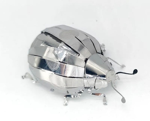 Het Lieveheersbeestje Metalen Bouwpakket van SlimSpul nederland b.v. is een gedetailleerde metalen lieveheersbeestje sculptuur met zes poten en twee antennes, afgebeeld op een witte achtergrond, die lijkt op een insecten modelbouwpakket.