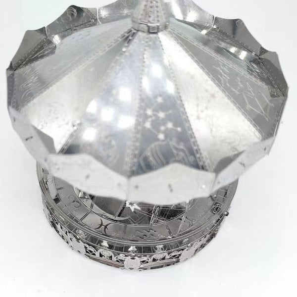 Een zilveren object met een ronde bovenkant, dat doet denken aan de SlimSpul nederland b.v. Draaimolen met Sterrenbeelden Metalen Bouwpakket - Kermis Attractie.