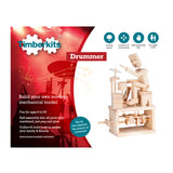 Een Drummer Houtconstructie Bouwpakket - Ritmisch Bewegend Model (Timberkits) van SlimSpul nederland b.v. toont een houten drummer, productinformatie en een rode achtergrond met instrument silhouetten; gepromoot als een doe-het-zelf pakket voor de leeftijd 9-90 jaar.