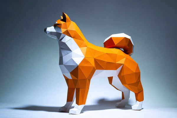 Het Shiba Inu 3D Papier Model - Japans Hondenras Bouwpakket van SlimSpul nederland b.v. is een geometrische sculptuur met oranje en witte facetten, voorstellende een alerte hond met een gekrulde staart tegen een effen achtergrond.