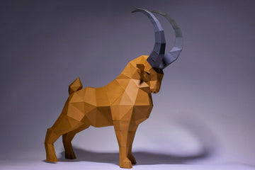 Het SlimSpul nederland b.v. Steenbok 3D Papier Model - Imposant Bergdier Bouwpakket toont een bruine, veelhoekige steenbok met grote grijze horens, met een hoekig ontwerp op een neutrale achtergrond.
