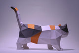 De Munchkin Kat 3D Papier Model - Raskat met Korte Pootjes van SlimSpul nederland b.v. is een geometrische papier sculptuur kit met witte, zwarte, grijze en oranje facetten voor een calico look, afgebeeld tegen een effen lichte achtergrond.