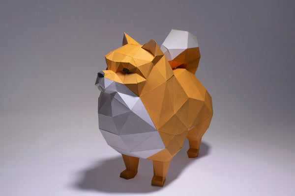 Het SlimSpul nederland b.v. Pomeriaan (Dwerg Keeshond) 3D Papier Model - Pluizig Honden Bouwpakket is een geometrische low-poly DIY papieren sculptuur in oranje, wit en grijs; perfect voor modelbouw fans en hondenliefhebbers.