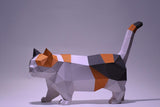 De Munchkin Kat 3D Papier Model van SlimSpul nederland b.v. is een geometrische, low-poly DIY sculptuur van een kortbenige kat (Raskat met Korte Pootjes) in calico kleuren, staand op handen en voeten met zijn staart omhoog.