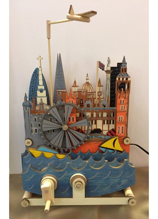 De Londen Stadsgezicht Houtconstructie - Bewegend Miniatuur van SlimSpul nederland b.v. is een houten doe-het-zelf-automaat met Londense oriëntatiepunten, een gele boot op golven, een vliegtuig erboven en twee zwengels aan de voet.
