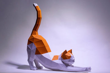 Oranje-witte rekkende kat als groot geometrisch 3D papiermodel vanuit driekwart vooraanzicht