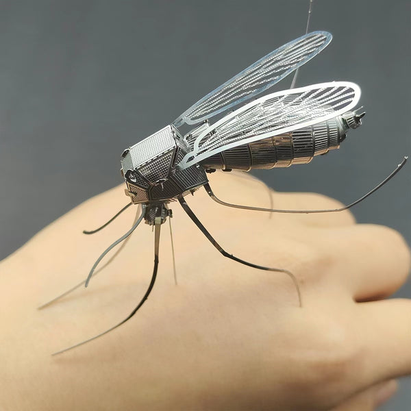 Het Tijgermug Metalen Bouwpakket - Gedetailleerd Insect Model van SlimSpul nederland b.v. toont een metalen tijgermug met fijne vleugels en poten, roestend op een hand voor een grijze achtergrond.