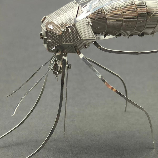 Een close-up van het Tijgermug Metalen Bouwpakket van SlimSpul nederland b.v.: een gedetailleerd insectenmodel met fijne potentie en gesegmenteerd lijf, afgebeeld tegen een effen grijze achtergrond.